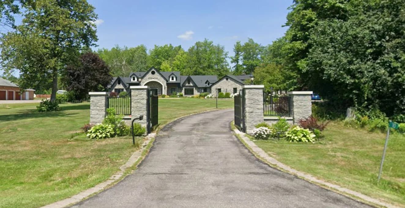 Supplied photograph looking along the driveway at 10 Fielding Court through stone gateposts toward the house and tree-lined lawn