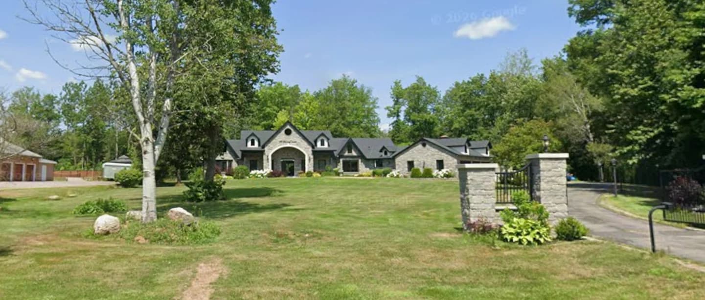 Wide supplied photograph of the street frontage at 10 Fielding Court showing the house, mature trees, lawn and driveway gate