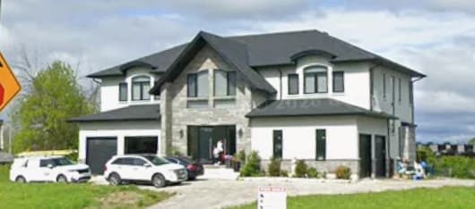 Supplied exterior photograph of 17 Ridge Road showing a two-storey house with pale walls, stone accents, broad windows and vehicles in the driveway