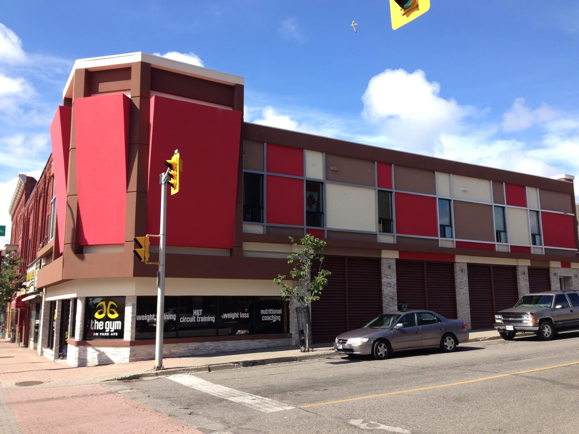 Wide street view of 30 Cumberland Street South's red and brown facade and ground-floor storefronts
