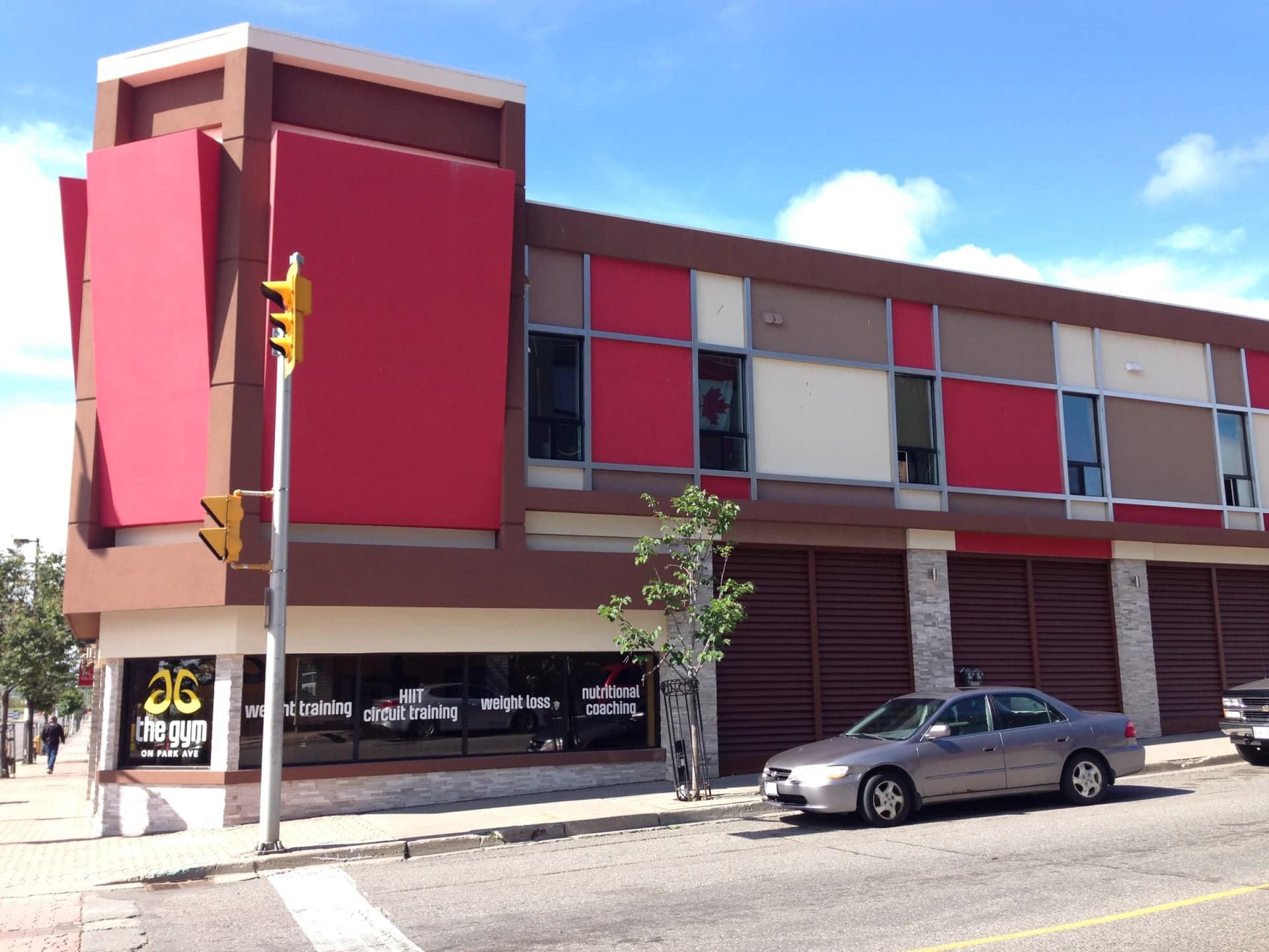 Street photograph of 30 Cumberland Street South showing the red corner tower, upper-floor windows, ground-floor storefronts and a parked car