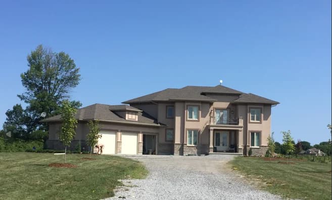 Supplied front photograph of 2367 Fourth Avenue showing the two-storey house, attached garages and gravel driveway beside the lawn