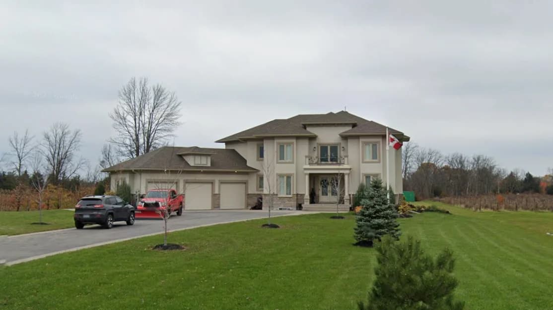Supplied photograph of 2367 Fourth Avenue from the driveway side showing the attached garages, entrance balcony and lawn