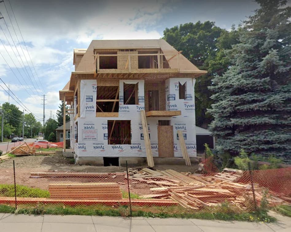 Supplied construction view of 160 Mountain Park Avenue showing timber framing, exterior sheathing and building wrap behind temporary site fencing