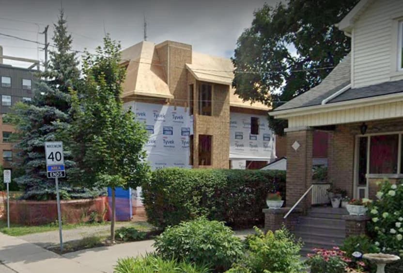 Supplied side construction view of 160 Mountain Park Avenue showing the timber roof structure and building wrap behind trees at the street corner