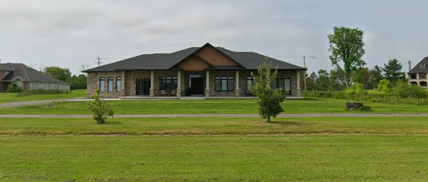 Supplied street view of the house at 3405 Niagara River Parkway with stone walls, timber-toned gables, a covered front porch and a broad lawn