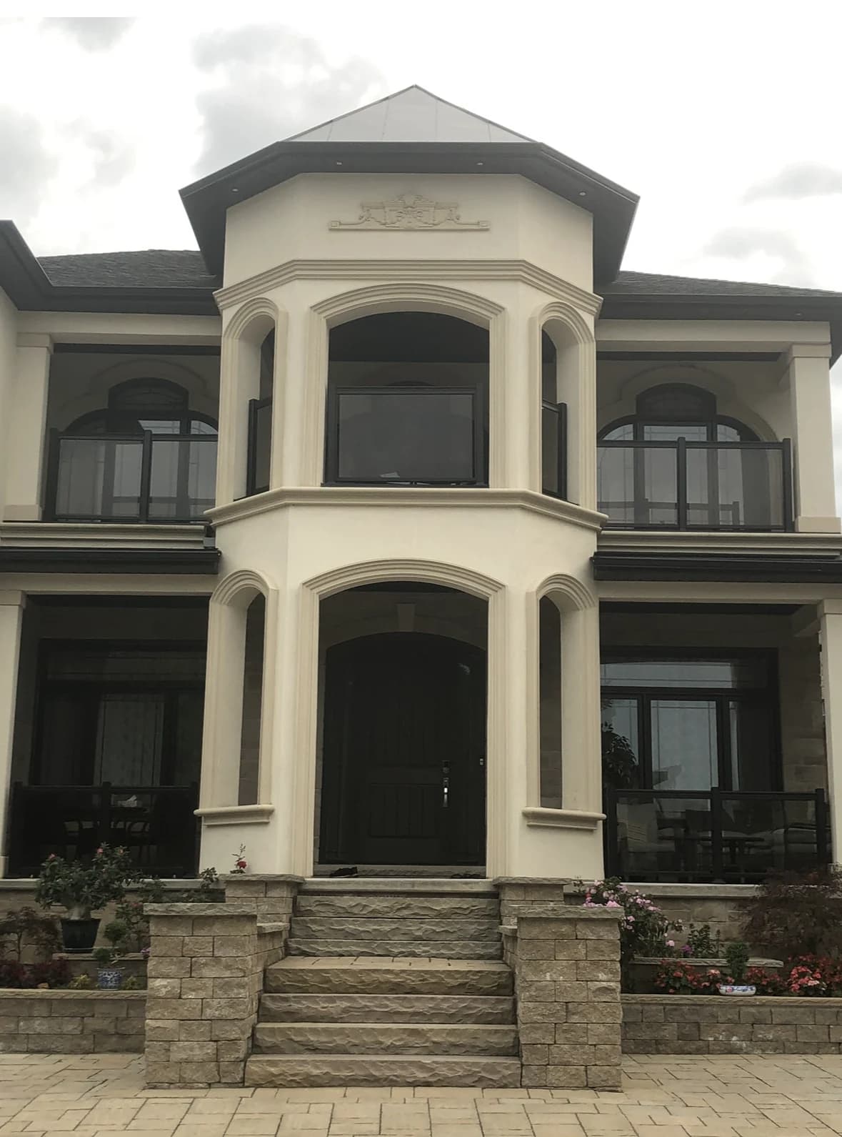 Entrance photograph at 66 Cielo Court showing stone steps, arched columns, a covered upper balcony and dark-framed windows