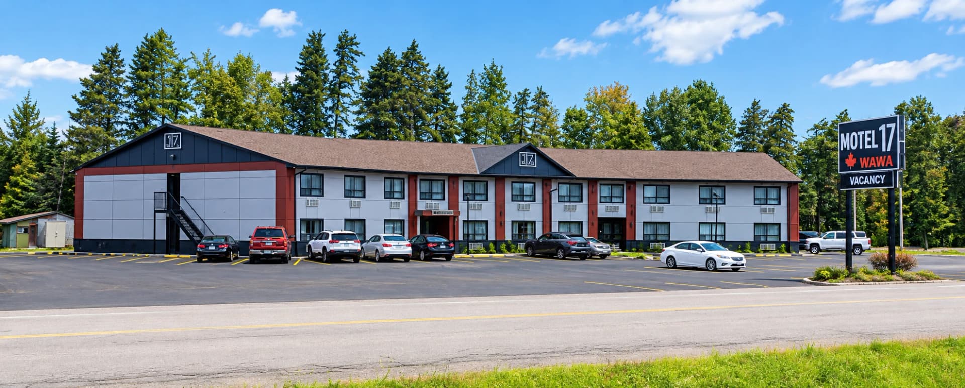 Daytime street photograph of Motel 17 in Wawa showing the two-storey building, exterior stairs, parked vehicles and the Motel 17 roadside sign
