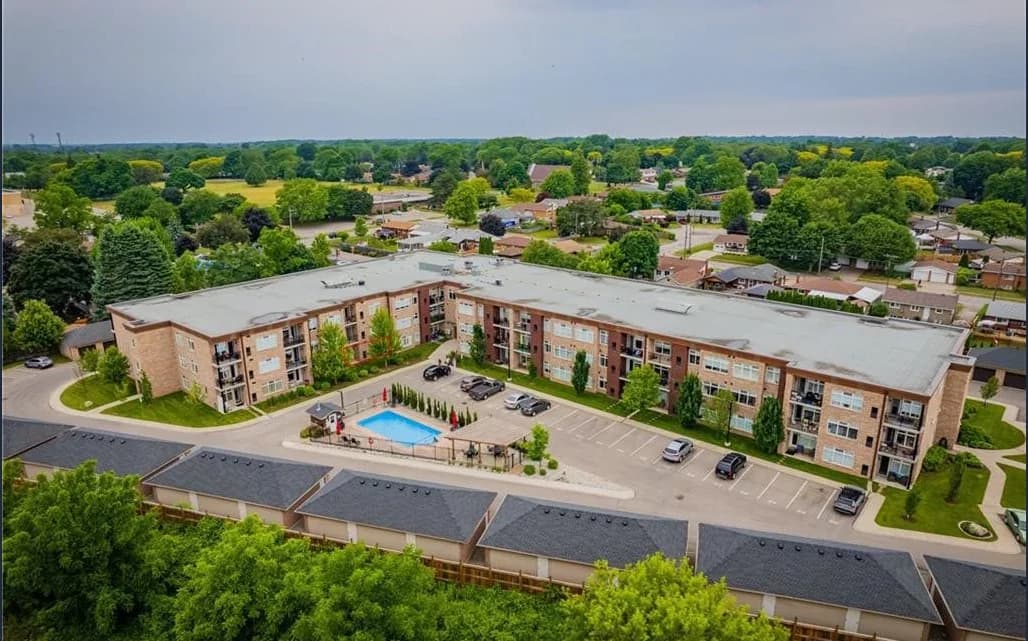 Aerial view of Olympia's L-shaped condominium building around a pool courtyard with surface parking and detached garages