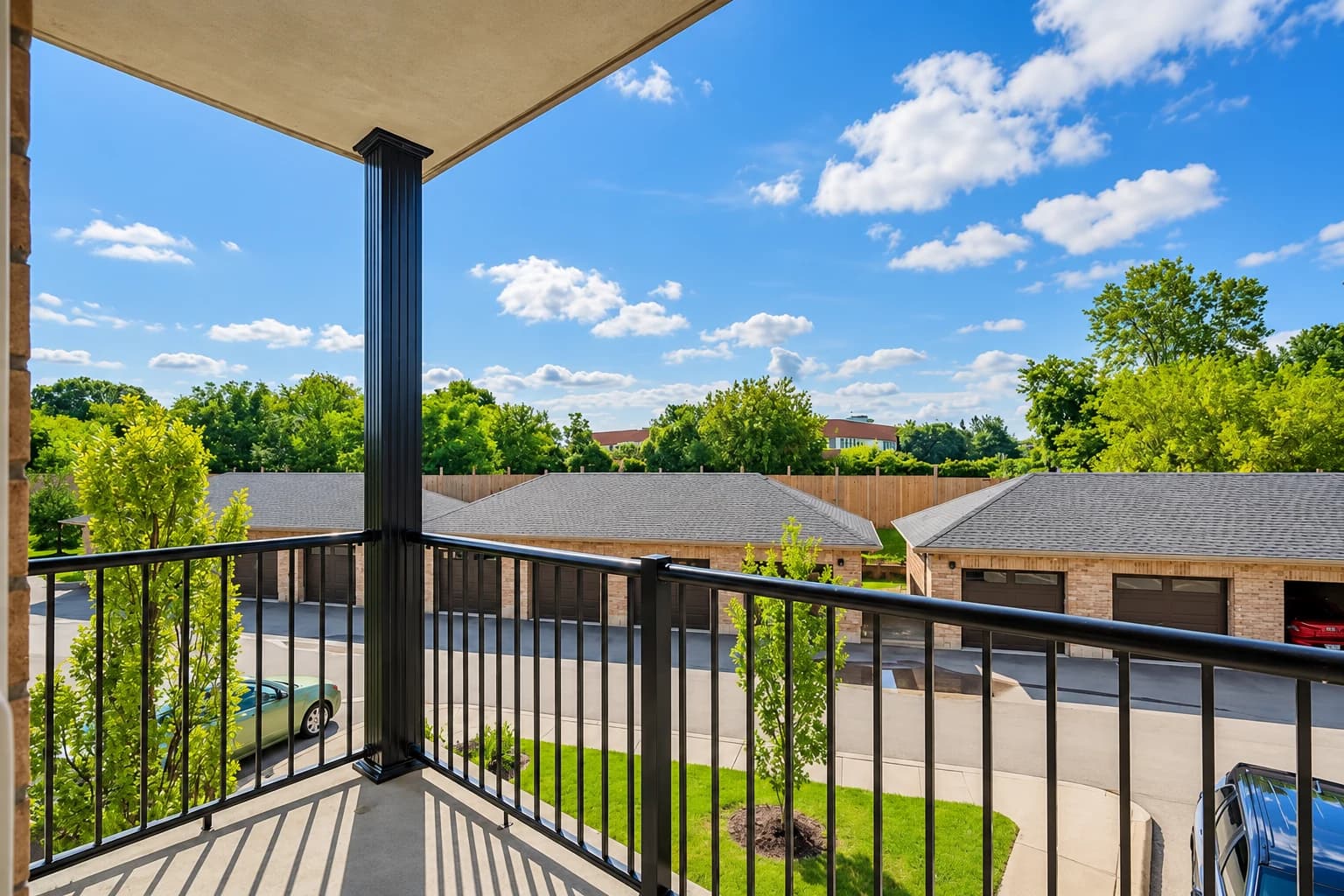View from a private balcony over brick garages, courtyard paving and trees