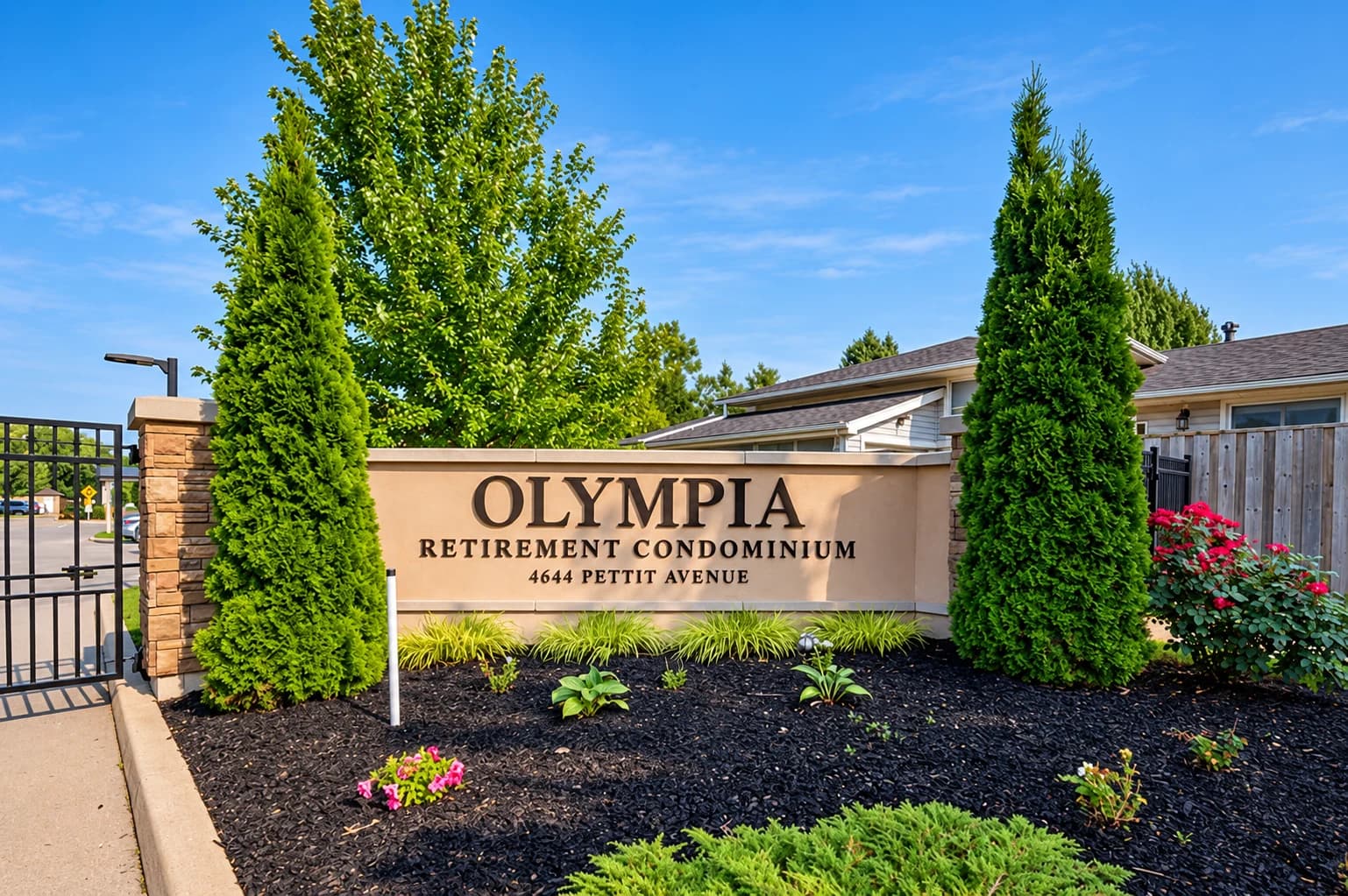 Olympia Retirement Condominium entrance sign framed by evergreens and landscaped planting