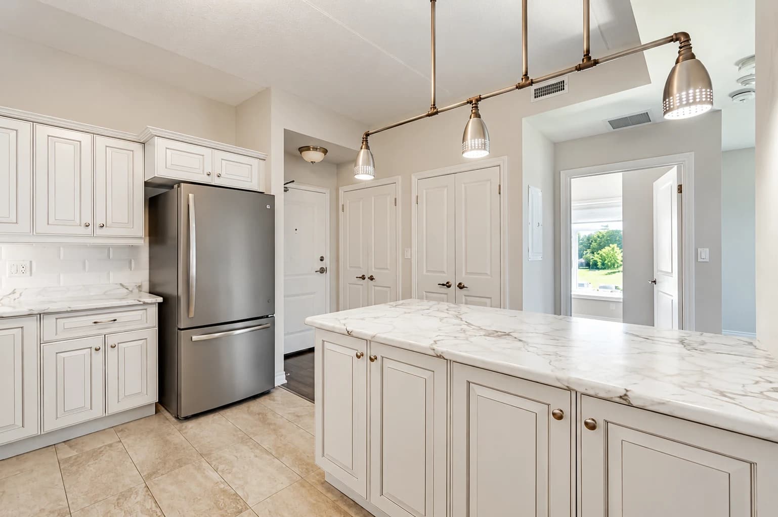 Reverse view of the white suite kitchen showing the peninsula, refrigerator and adjacent rooms