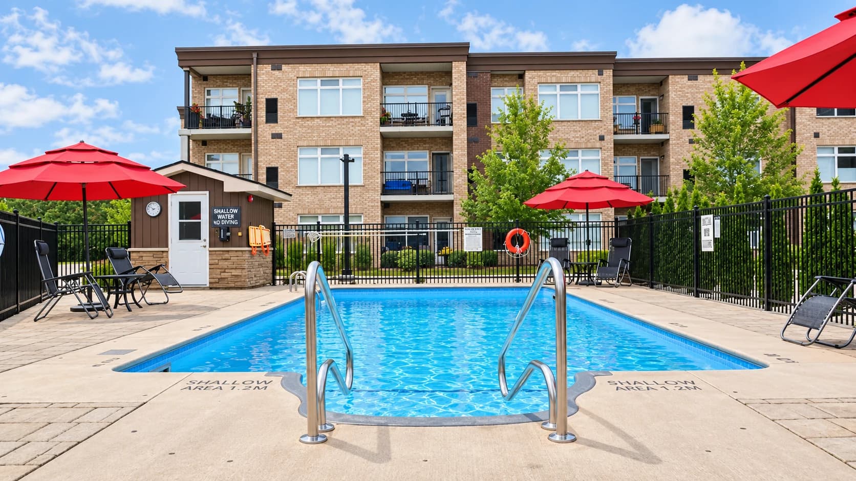 Outdoor swimming pool with red umbrellas and lounge chairs in front of Olympia's brick facade