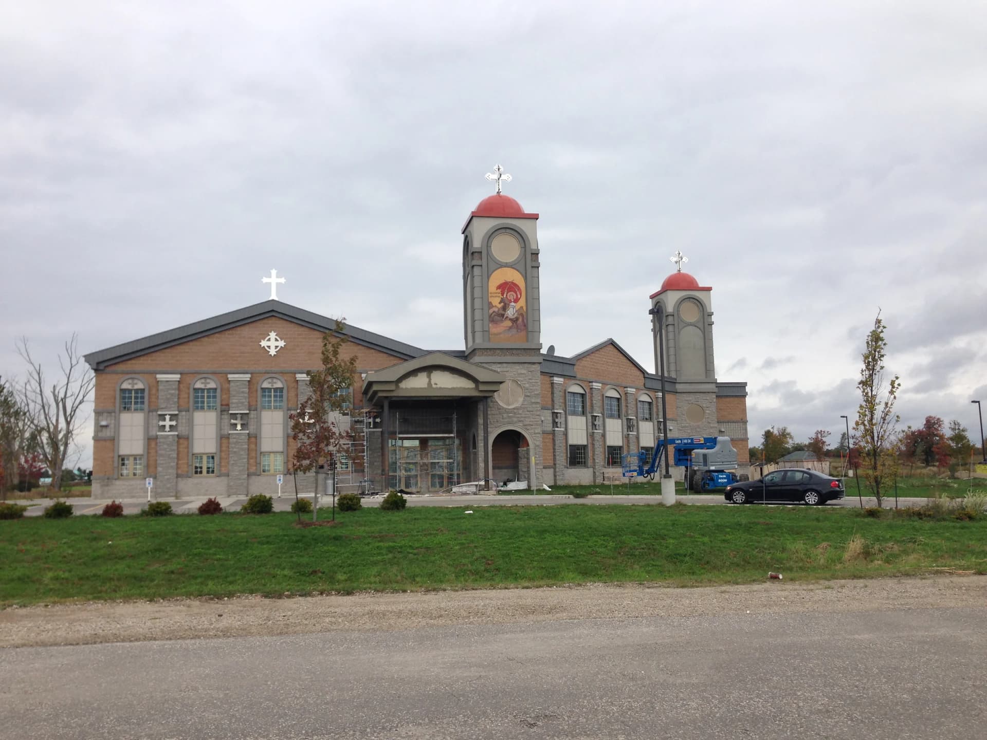 Wide view of St. Philopater Church in Guelph showing its entrance towers and landscaped grounds