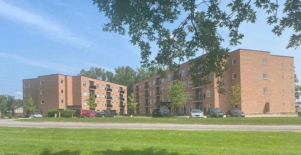 Two four-storey brick residential buildings on Swayze Drive with recessed balconies, white-framed windows and landscaped lawns