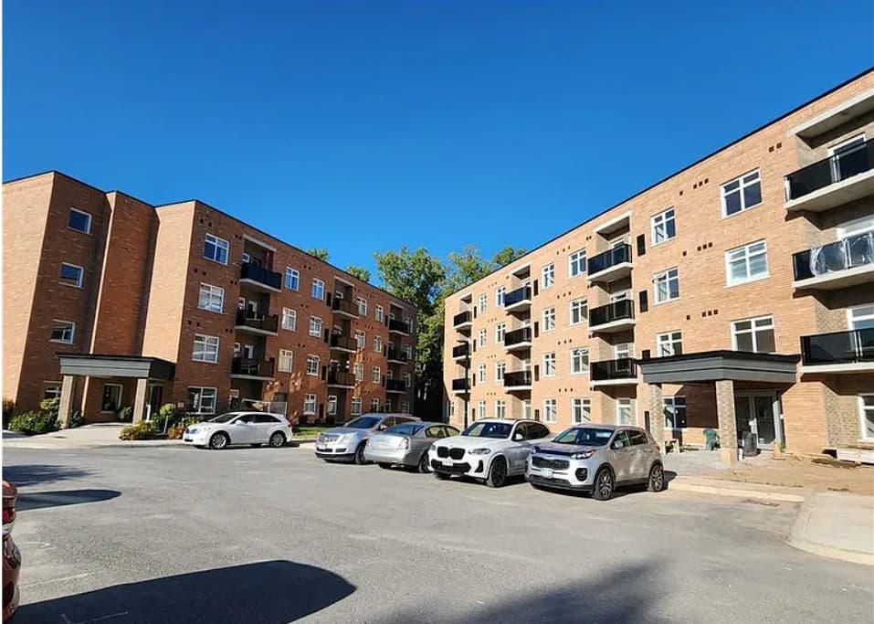 Swayze's brick residential buildings around a paved parking courtyard, with recessed balconies and flat entrance canopies