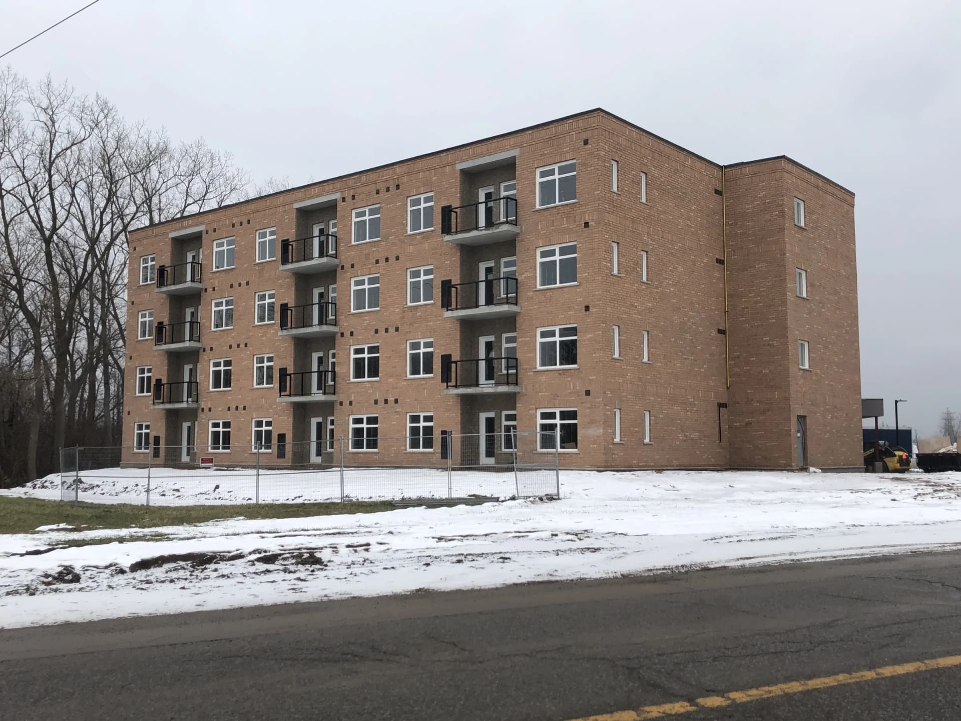 Four-storey brick residential building in Niagara Falls with recessed balconies and white-framed windows
