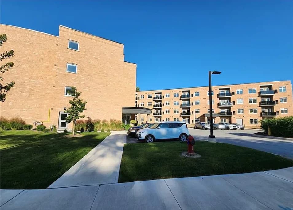 Concrete walkways through landscaped lawns connect Swayze's brick buildings and courtyard, with balconies and parking beyond