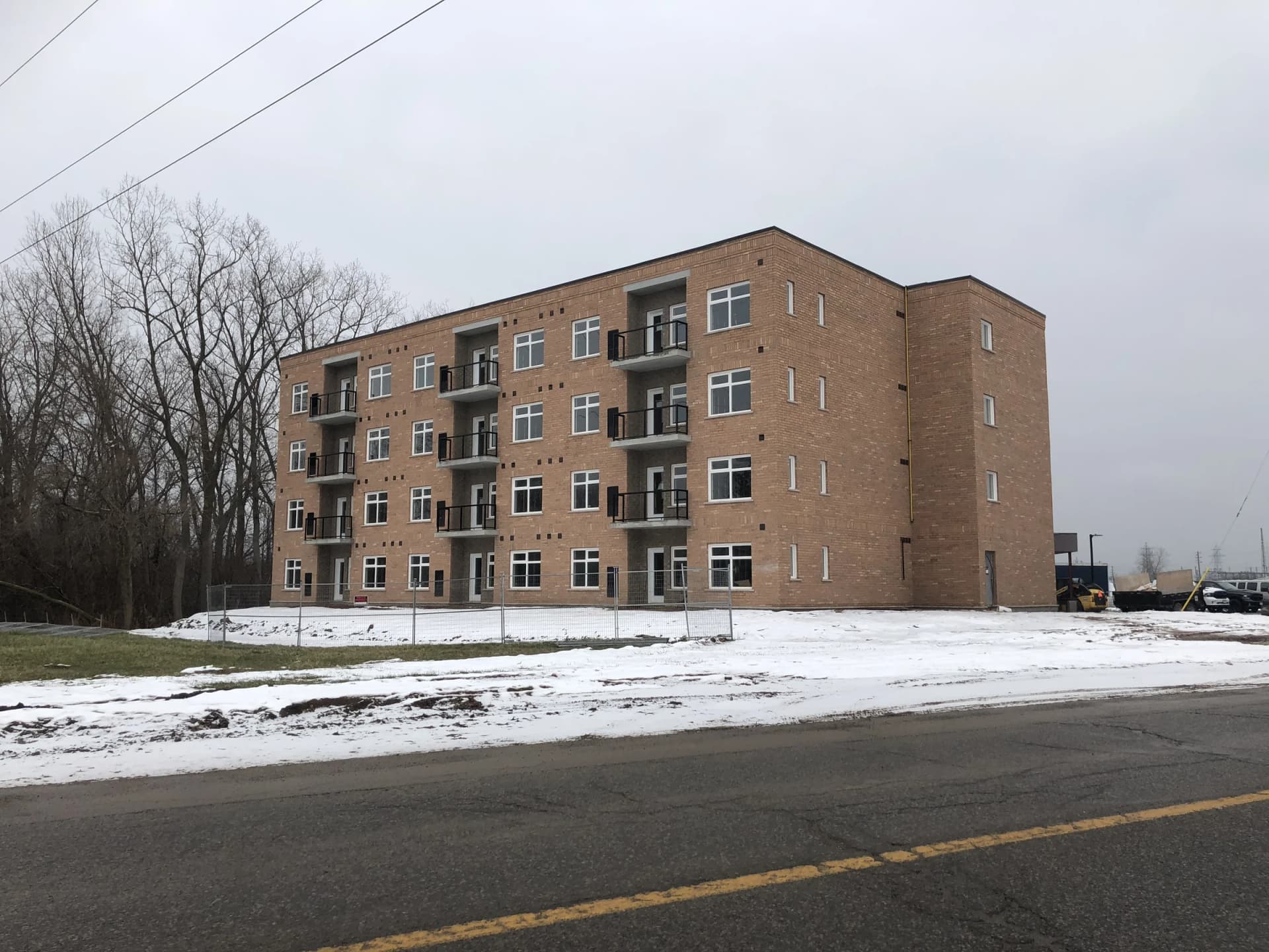 Wide supplied winter street photograph of the apartment building at 5629 Swayze Drive with brick walls, balconies, snow-covered grounds and the road in front