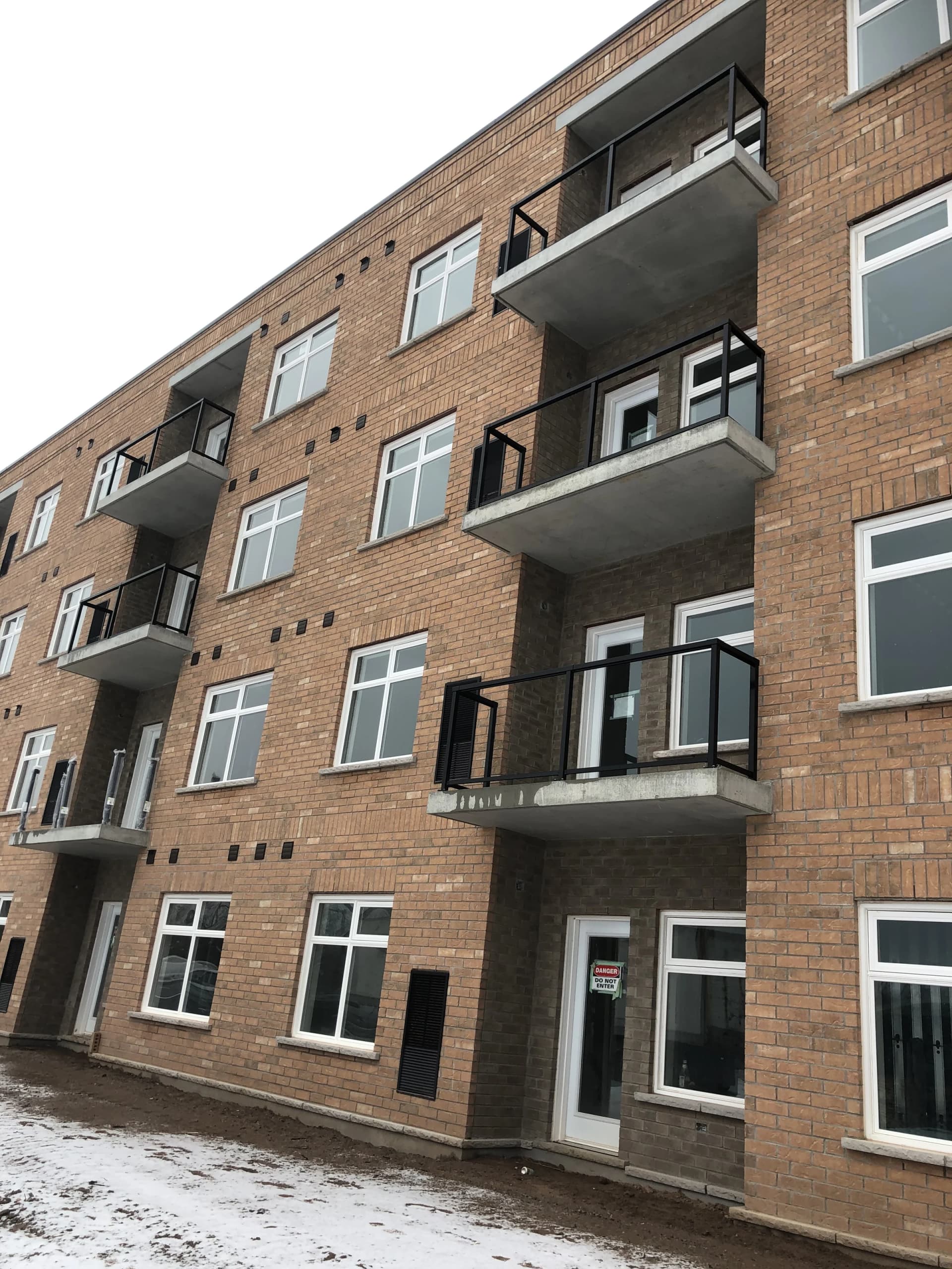 Supplied winter photograph along the brick balcony elevation at 5629 Swayze Drive with dark railings and ground-floor patio doors