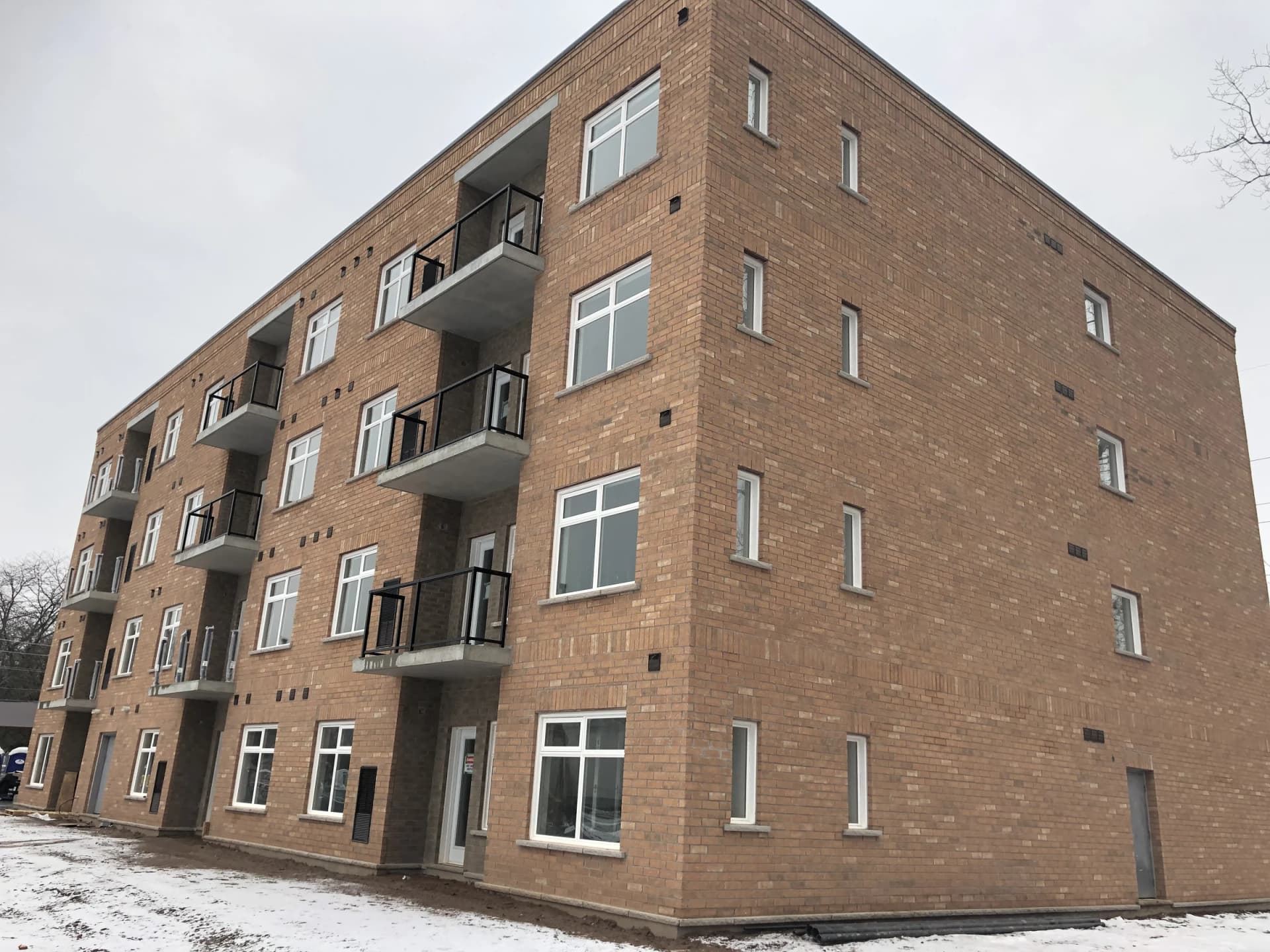 Supplied winter photograph of the apartment building at 5629 Swayze Drive showing its brick corner, projecting balconies and snow-covered ground
