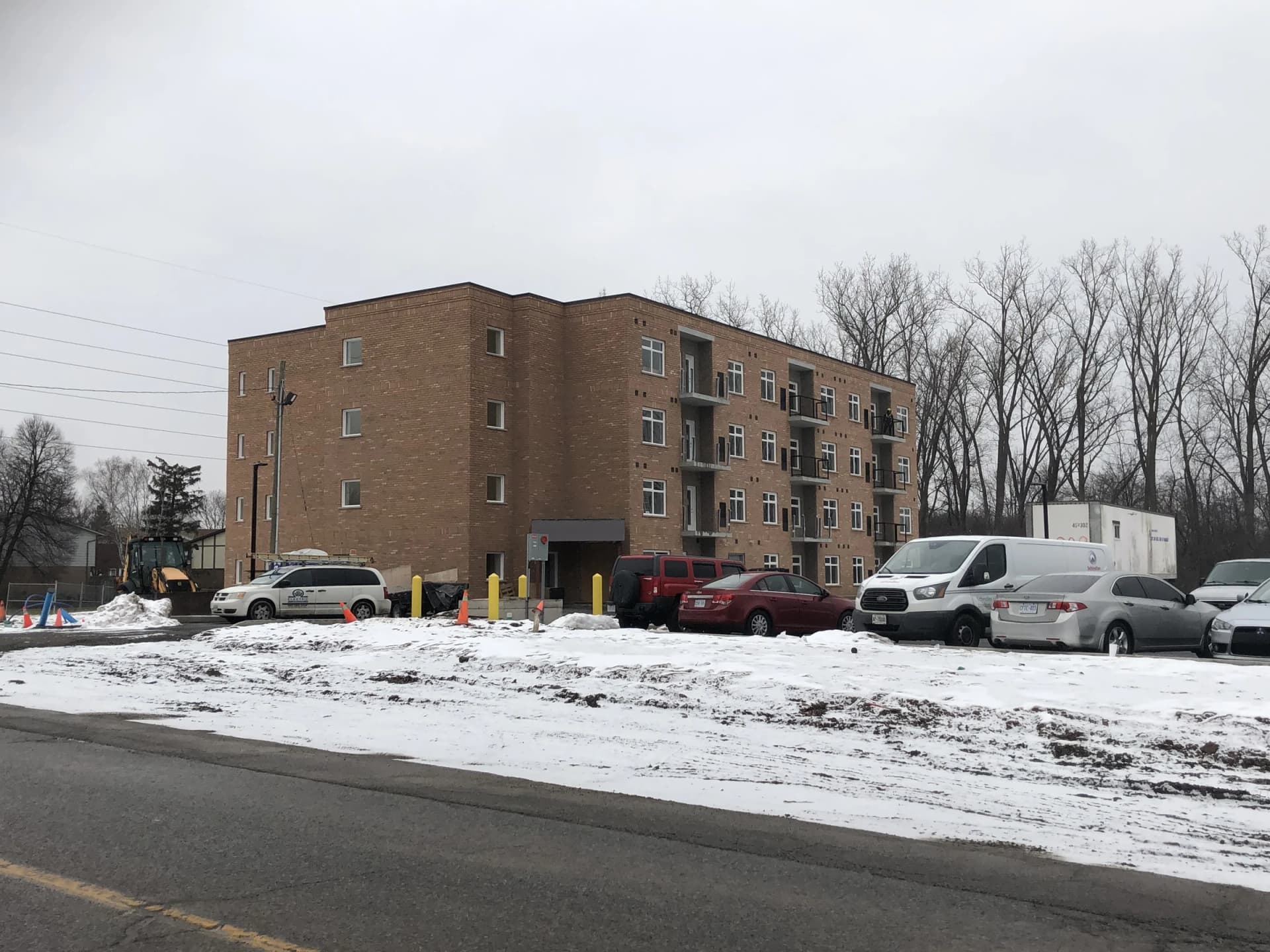 Supplied winter photograph of the entrance side at 5629 Swayze Drive showing the brick building, projecting balconies and parked vehicles