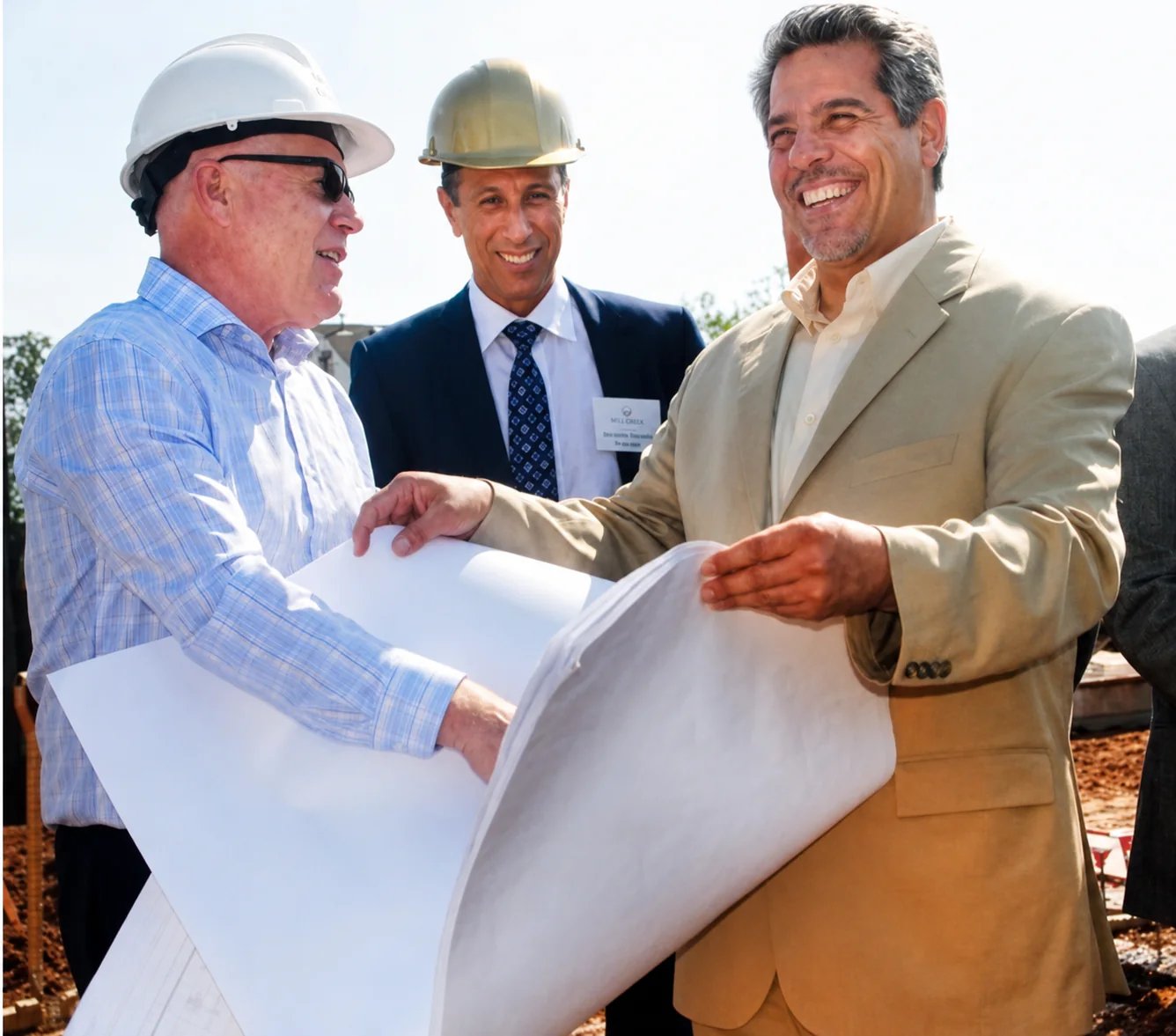 Project collaborators gathered around architectural drawings at a construction site.